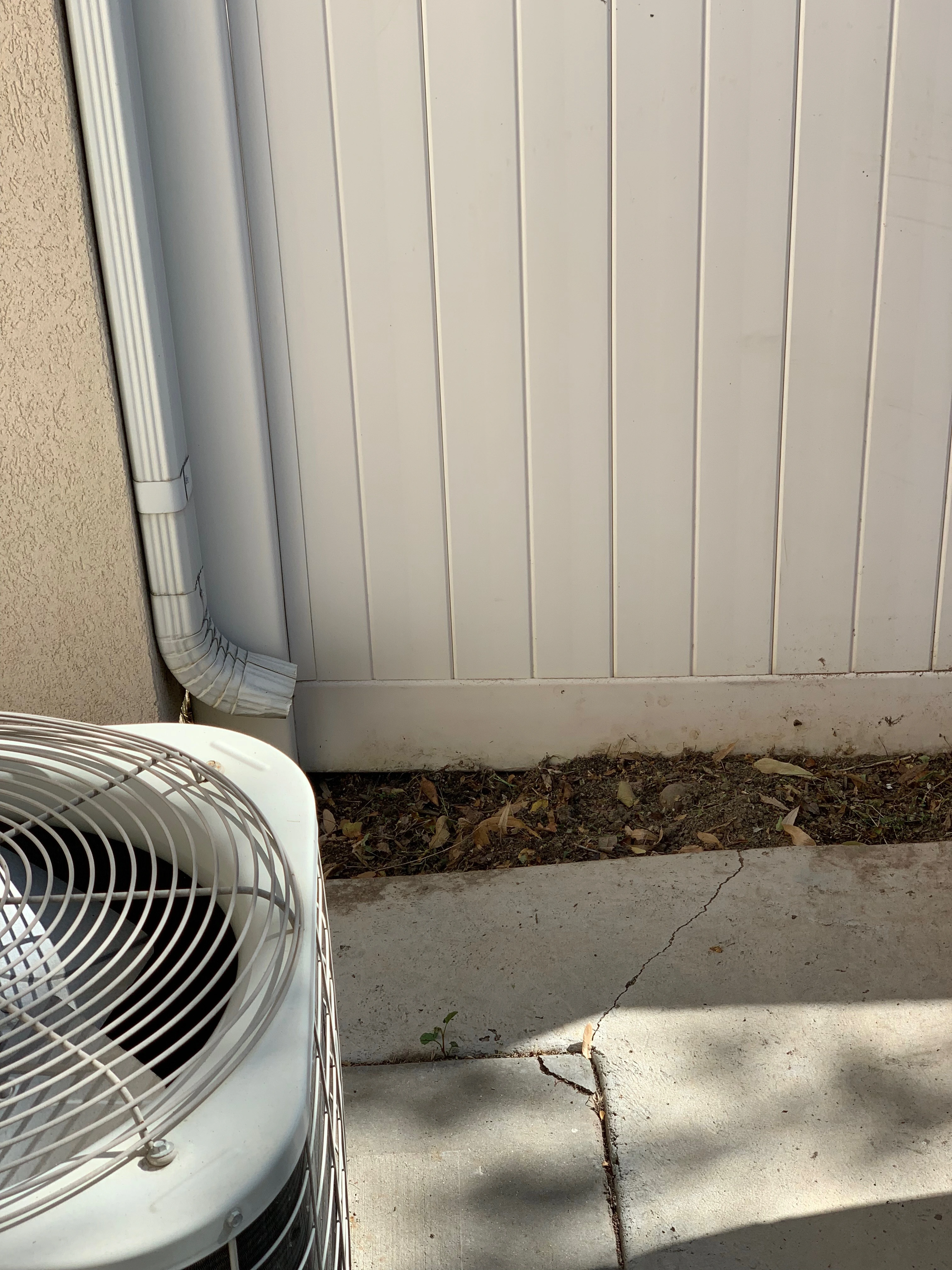 The same strip beside the fence and AC unit cleared of weeds after the ModJobs cleanup